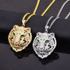 Diamond-encrusted tiger head pendants in gold and silver, featuring vibrant green eyes and intricate designs.